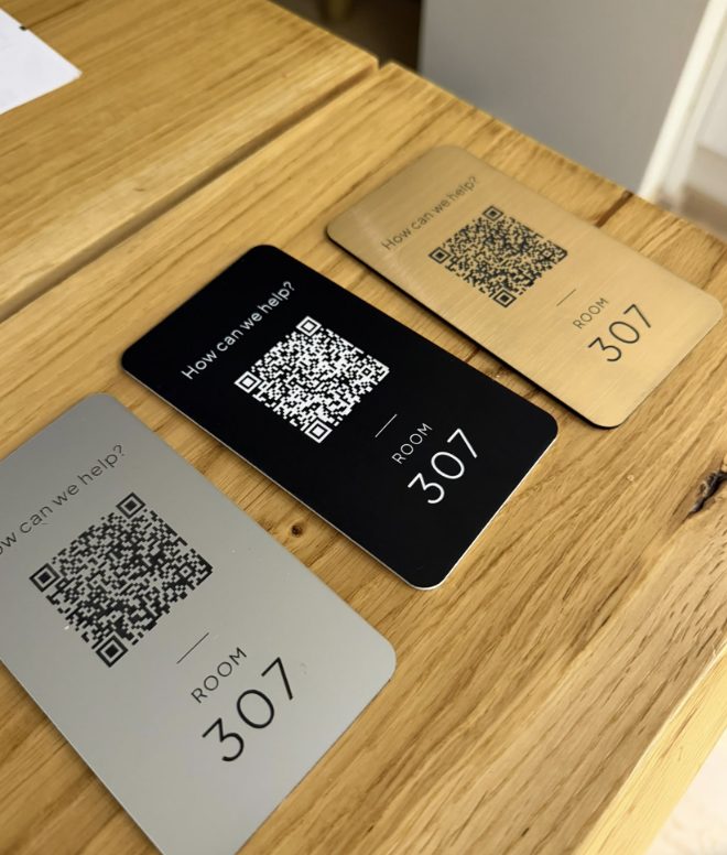 Hopeinen, musta ja kultainen QR-laatta vierekkäin puupinnalla